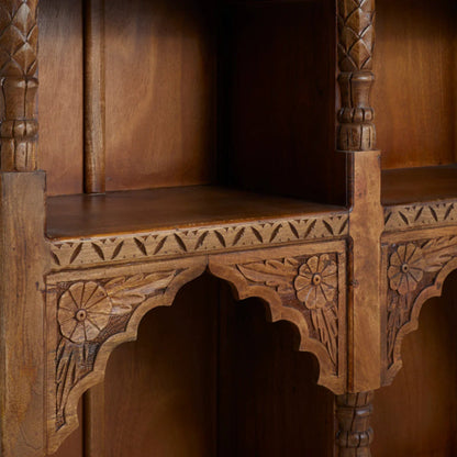 Floral carved bookcase in brown solid wood, edge detail view showing flower reliefs, scalloped trim and carved shelf borders.