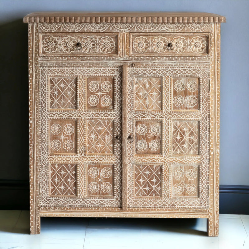 Floral carved storage cabinet in pale wood, shown in a front view with two drawers above patterned double doors.