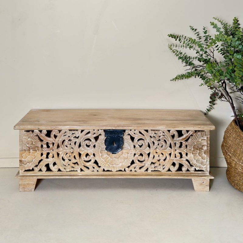 Floral carved toy chest in rustic solid wood, front view displaying the central black latch and sweeping pierced scrolls.