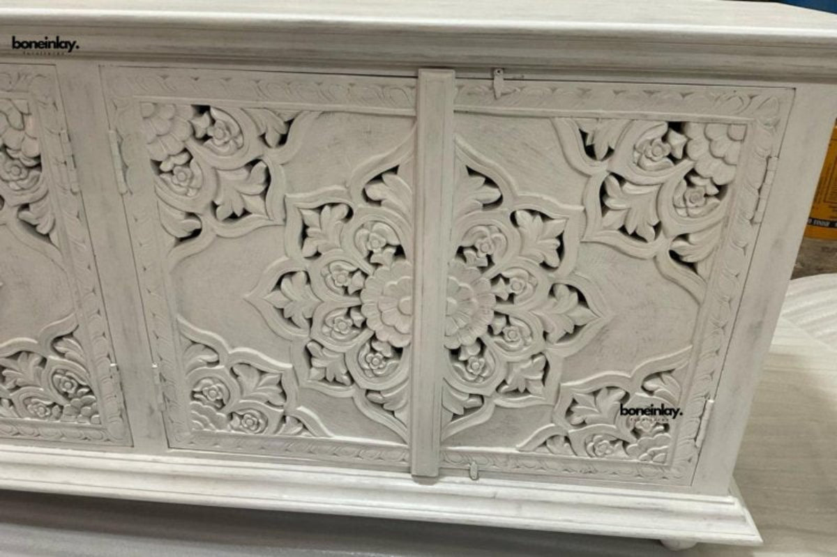 Floral carved wood sideboard in a close-up of the carving detail, showing raised petals and curving lines.