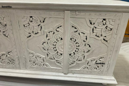 Floral carved wood sideboard in a close-up of the carving detail, showing raised petals and curving lines.