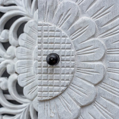 Floral door storage buffet in rustic wood, close-up of a dark round door knob against textured flower carving.