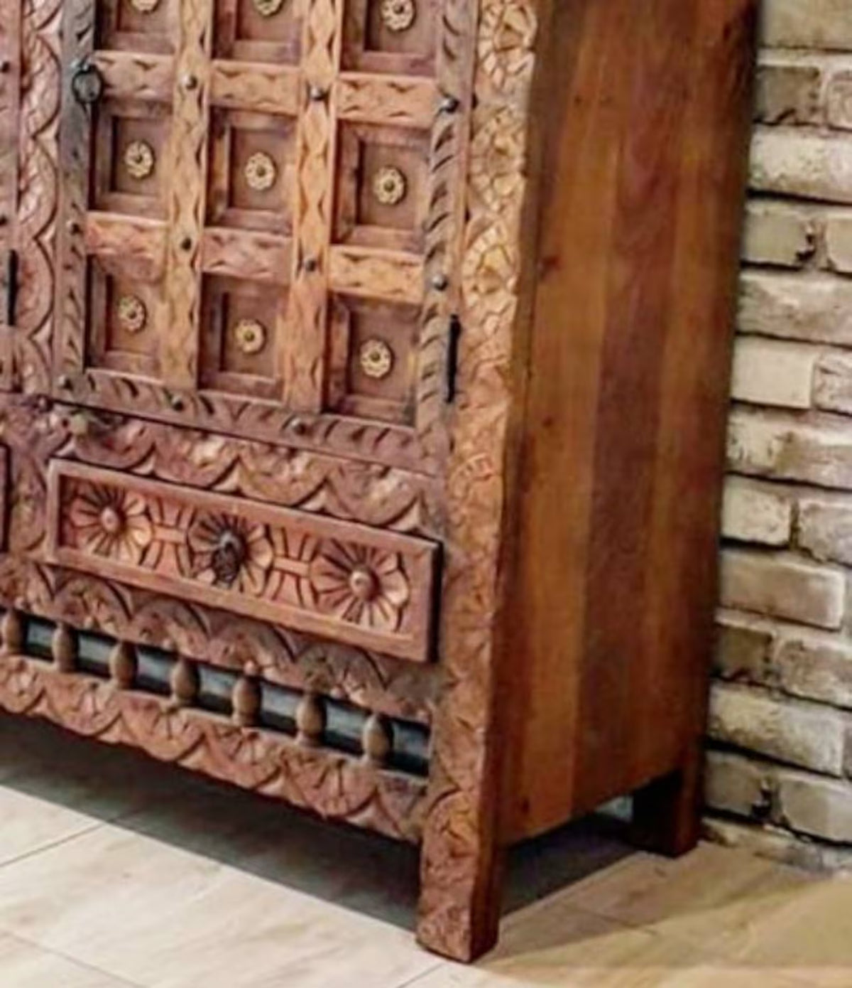Floral drawer wood credenza in a corner detail view, showing rustic carved trim, the lower drawer and plain wood side.