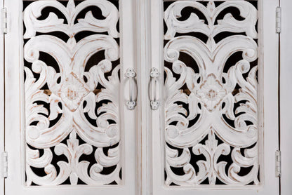 Floral fretwork accent cabinet in rustic solid wood, close-up of drawer handle-style pulls on carved cupboard doors.