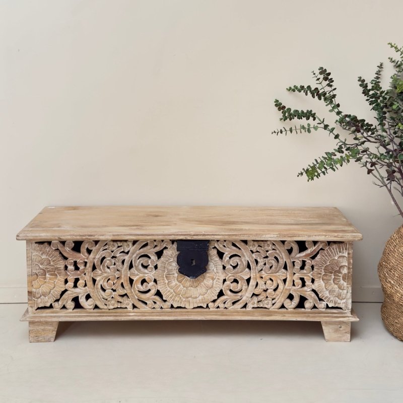 Floral solid wood chest with a rustic finish, front view showing pierced scroll carvings, a black latch and short feet.