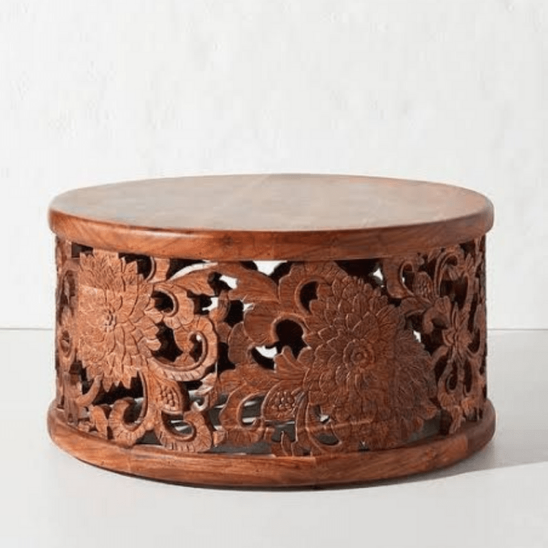 Floral wood accent table in a deep natural finish, front view revealing carved blooms and an open drum base.