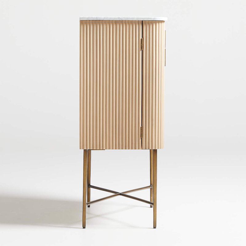 Fluted door cocktail cabinet viewed from a narrow side angle, showing brass hinges and pull on the front edge.
