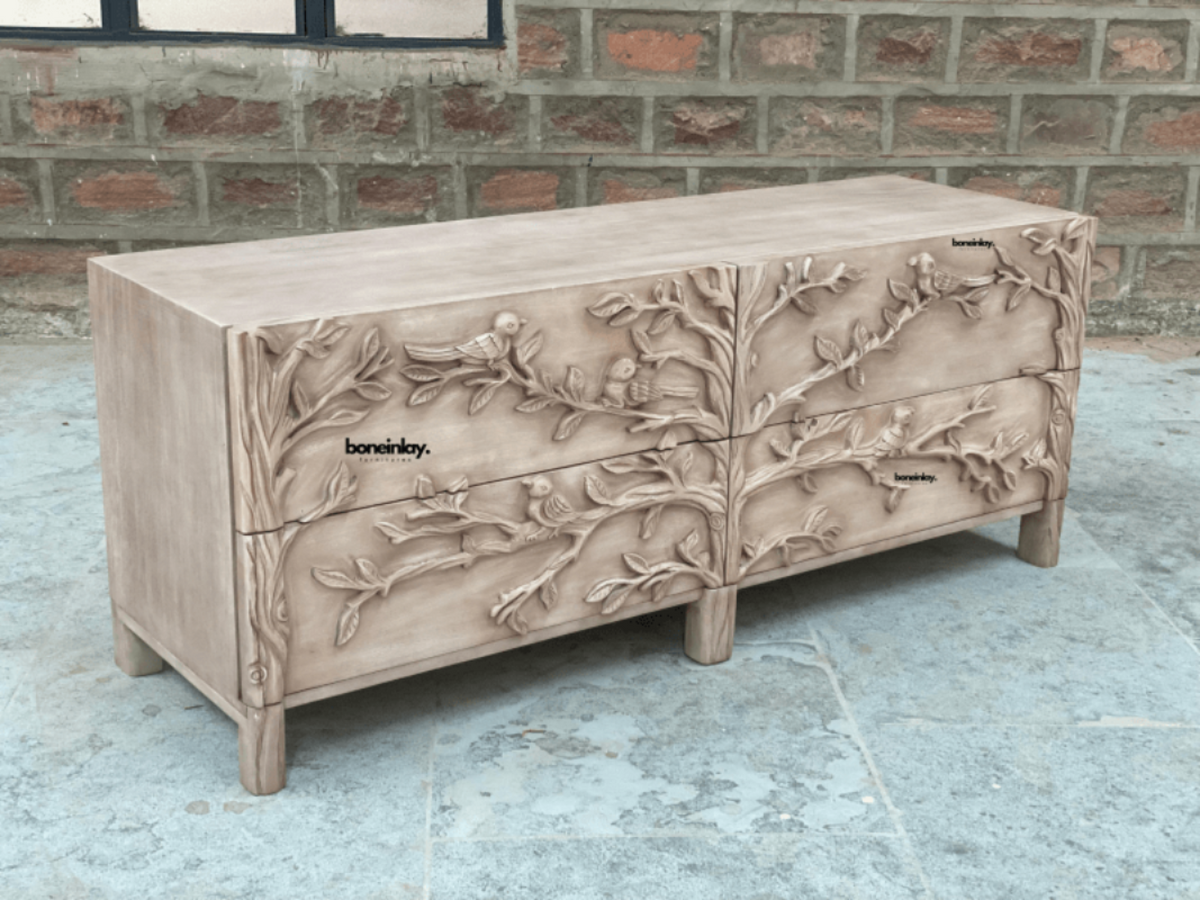 Four-Drawer Wood Cabinet with carved bird motifs, front view at an angle showing its long top and short legs.