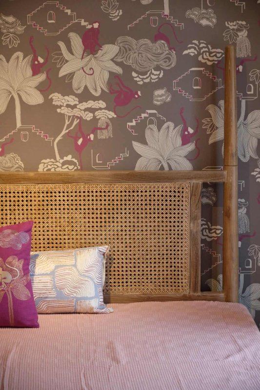 Four-poster bed frame with woven cane panels and overhead rails.