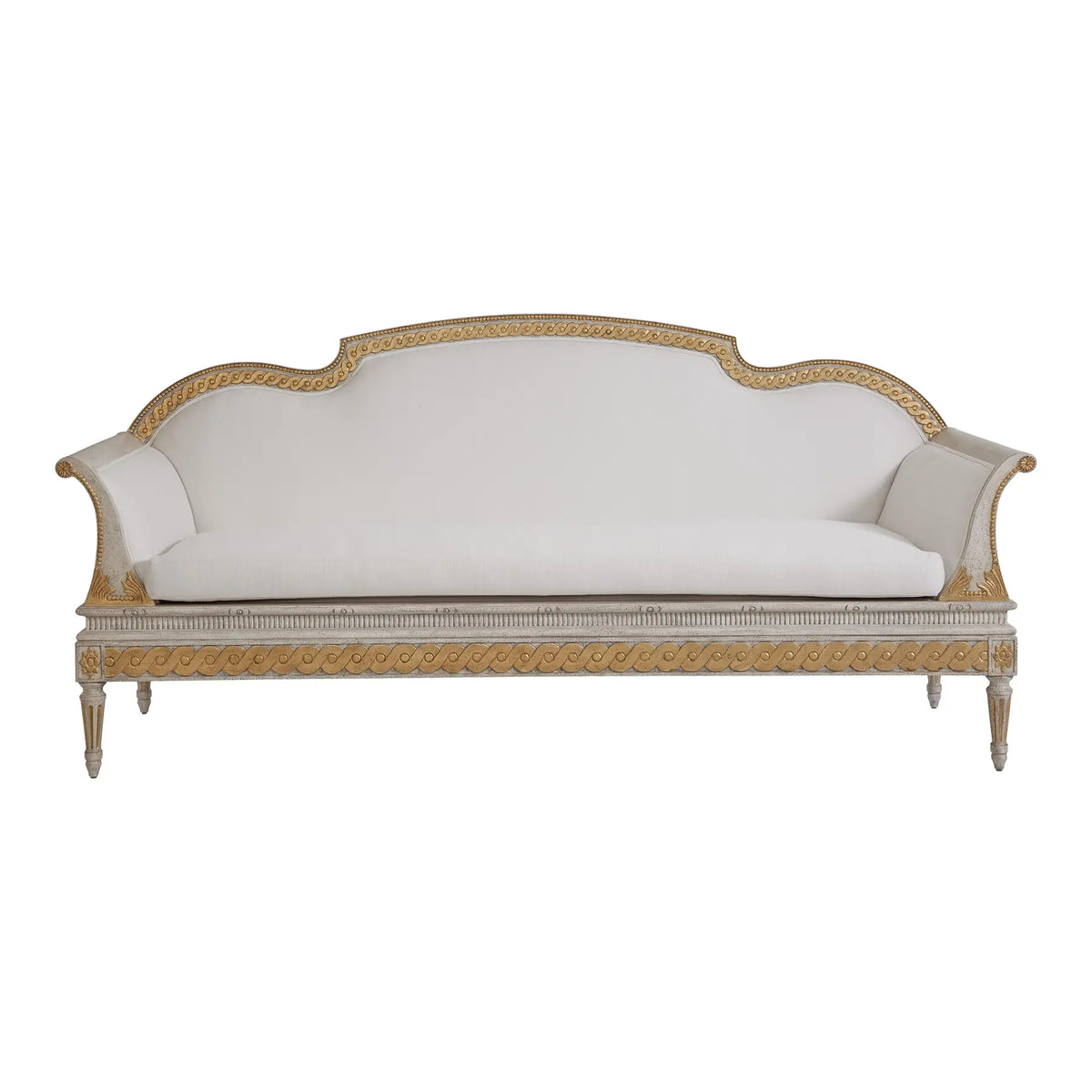 Hand-carved French Neoclassical solid wood sofa with gold leaf ribbon moldings, scrolled arms, and white upholstery in distressed cream finish.