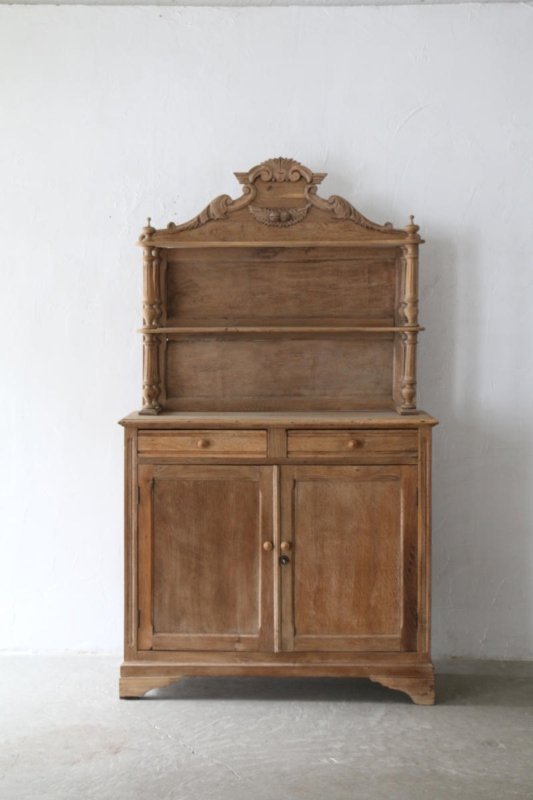 Front view of a rustic solid wood French Provincial style buffet and hutch with an ornate hand-carved top crown, open display shelves, two drawers, and a double-door cabinet.