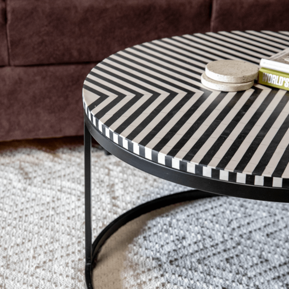 Geometric black and white bone inlay round coffee table with sturdy black metal base, handcrafted artisan center table styled in a contemporary living room