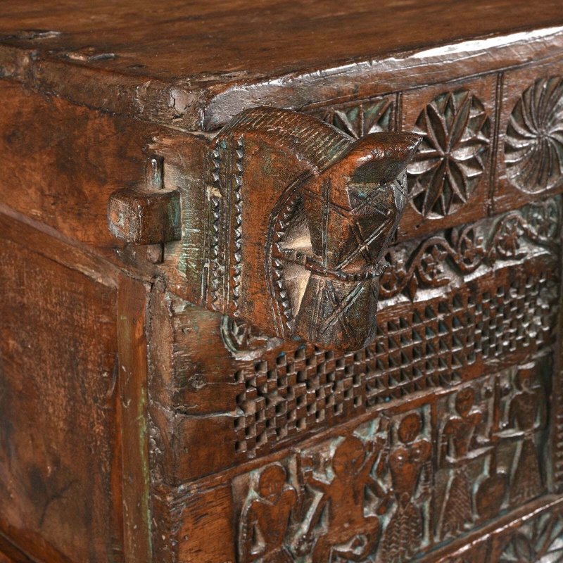 Geometric carved blanket chest in natural wood, corner detail view showing the left projection and textured panels.