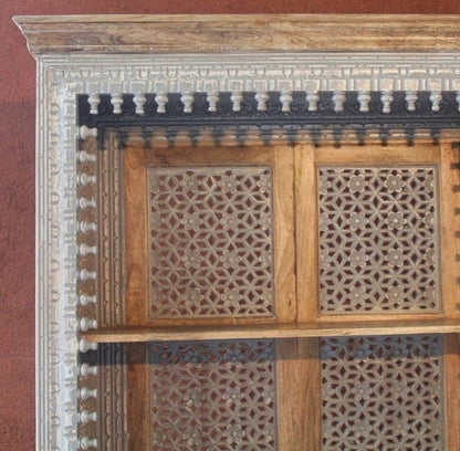 Geometric carved shelving unit in rustic wood, edge detail view showing decorative trim and star-pattern fretwork.