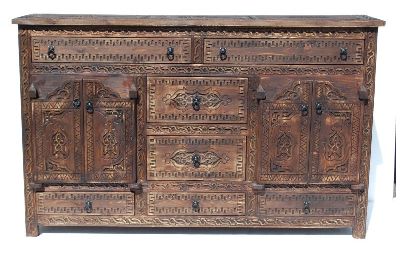 Geometric carved timber credenza in rustic wood, front view with a visible top surface, closed doors and ornate drawers.