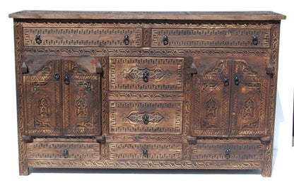 Geometric carved timber credenza in rustic wood, front view with a visible top surface, closed doors and ornate drawers.