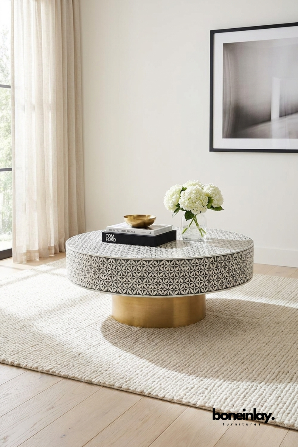 Round black and white bone inlay coffee table with floral geometric pattern and brushed brass pedestal base styled in a neutral living room