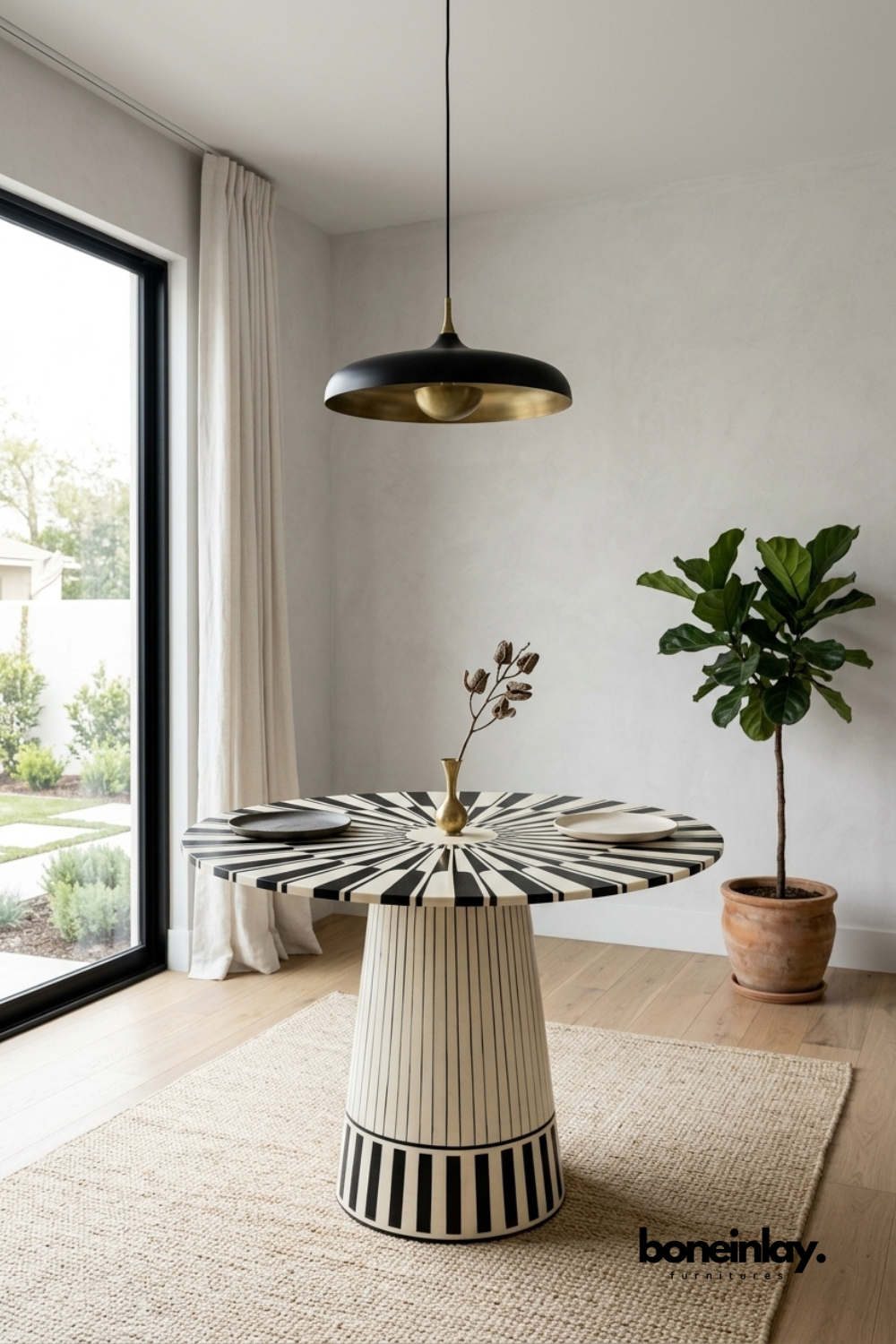 Round bone inlay dining table with a bold black and white striped pattern.
Radiating sunburst design covers the entire tabletop surface.
Matching fluted pedestal base continues the striped motif down to the floor.
Styled beneath a black and brass pendant light in a dining nook.