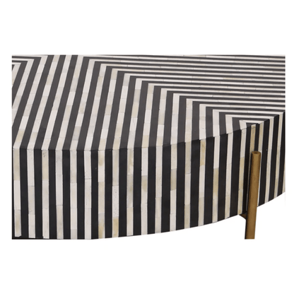 Close detail of black and white diagonal stripe bone inlay pattern on a handmade round coffee table surface with brass leg visible