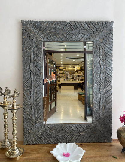 Gray botanical wall mirror in solid wood, front view displaying raised leaf carvings around the rectangular glass.