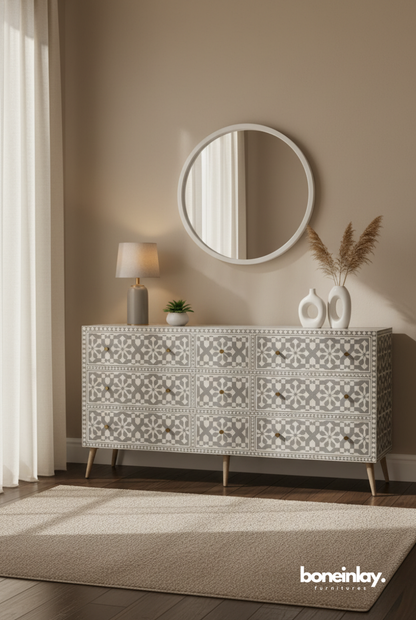 A luxury grey and white geometric bone inlay nine-drawer dresser featuring a sophisticated tile-mosaic pattern and an intricate inlaid border. The piece is accented with minimalist gold-toned hardware and supported by elegant, tapered wooden legs. Shown in a serene, modern interior under a circular wall mirror, this artisanal storage cabinet perfectly blends traditional Indian craftsmanship with a soft, contemporary Japandi aesthetic.