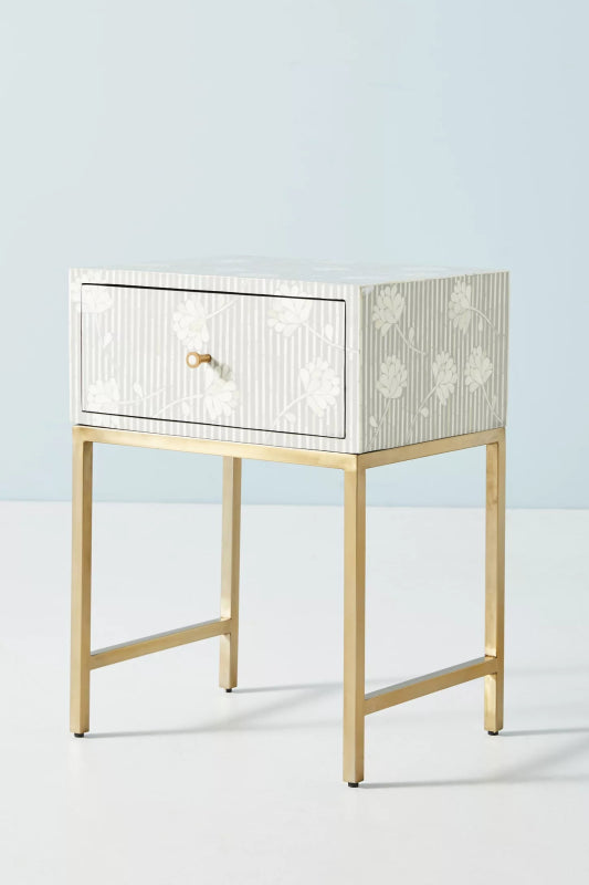 Handmade grey and white vertical stripe bone inlay bedside table with floating floral motifs, single drawer with brass ring pull, and polished gold metal base frame.