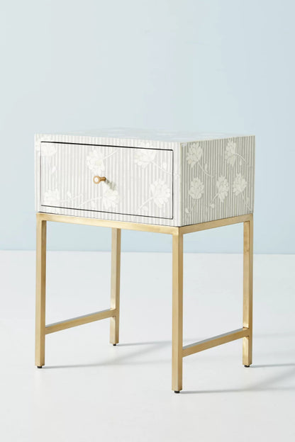 Handmade grey and white vertical stripe bone inlay bedside table with floating floral motifs, single drawer with brass ring pull, and polished gold metal base frame.