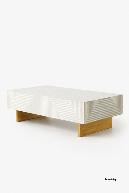 Artisan-crafted rectangular bone inlay coffee table featuring optical geometric zigzag stripe patterns in soft grey and white resin. Supported by warm brass plinth base legs against a clean studio backdrop, this contemporary cocktail table delivers modern elegance, handcrafted luxury, and timeless design to living spaces.