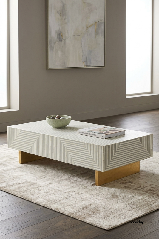 Handcrafted bone inlay rectangular coffee table styled on a plush beige area rug in a sunlit modern living room with abstract wall art. Showcasing a clean low-profile silhouette, geometric line motifs, and lustrous gold finish base supports, this designer center table brings understated luxury and bespoke charm to home interiors.