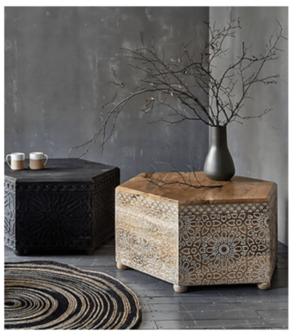 Hand-carved Albaron cocktail table shown beside a darker table, with its light-colored side facing forward.