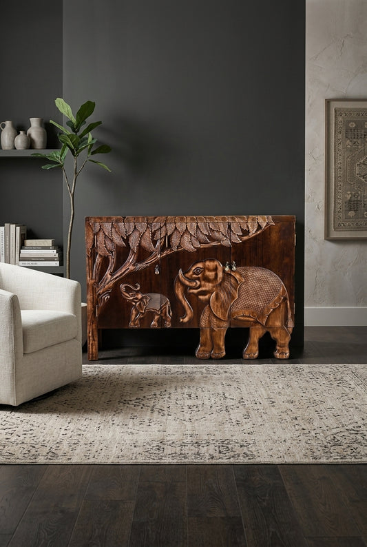 A carved wooden elephant sideboard displays a jungle motif across its doors, with the cabinet shown as a whole.