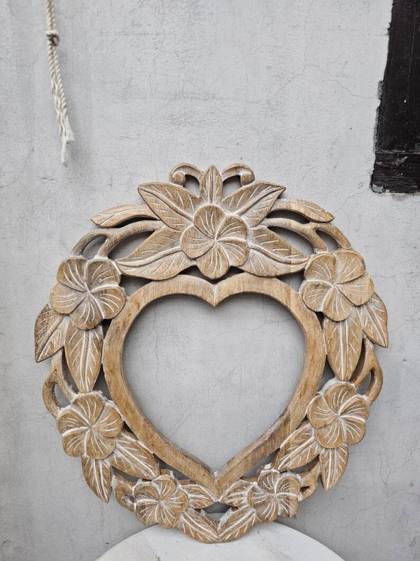 Hand-carved heart wall mirror in rustic solid wood, front view showing an open center surrounded by flowers and leaves.