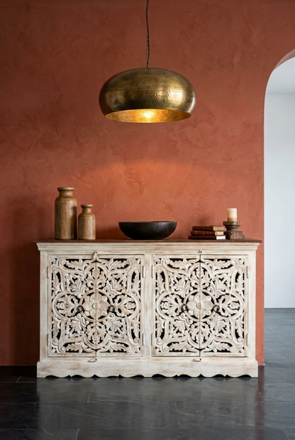 Rustic floral wood sideboard, front view with carved doors, styled against a terracotta wall beneath a pendant.