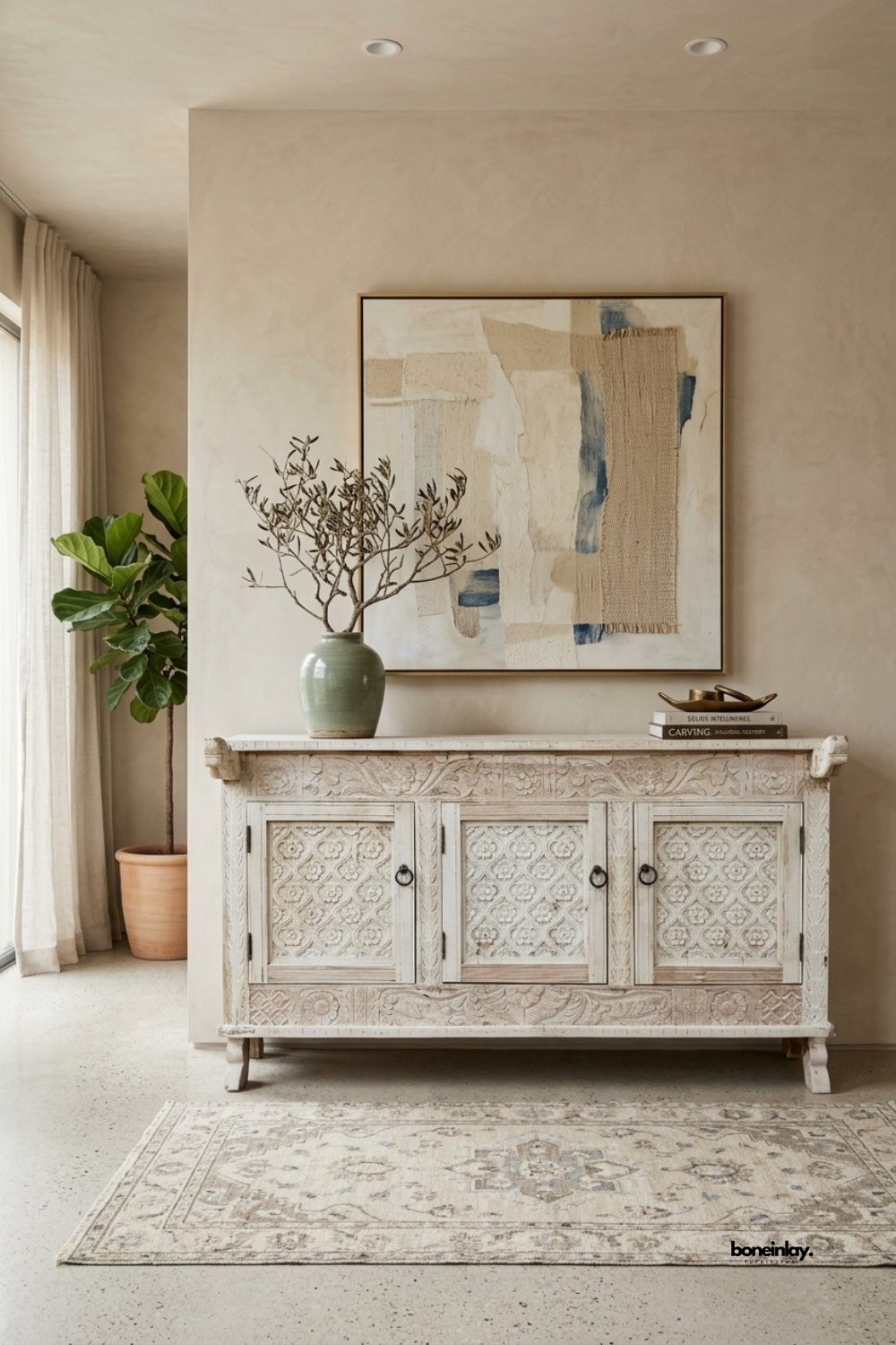 Hand-carved 3-door sideboard buffet featuring relief-carved floral panels, botanical
scroll borders, and classic dark ring pulls in a weathered whitewash finish.
Styled below textured abstract canvas art with a ceramic vase and vintage area rug,
this artisan credenza brings coastal bohemian elegance and versatile storage to modern dining rooms.