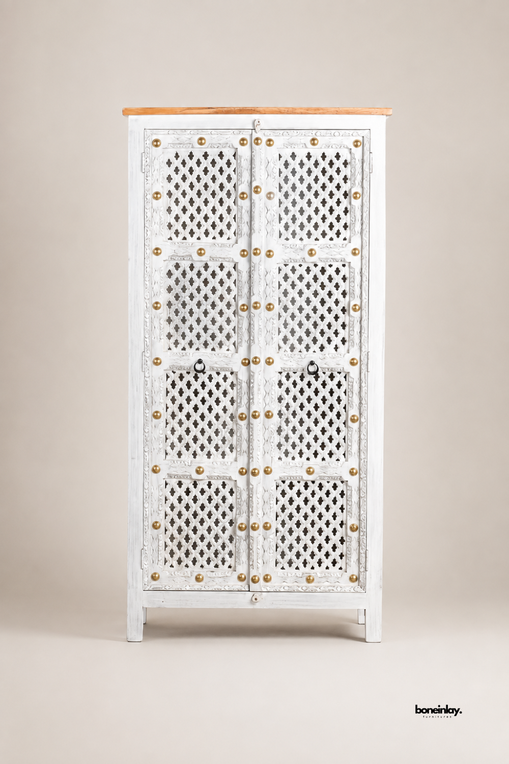 Artisan-crafted white washed wooden storage armoire showcased against a clean studio background, highlighting its intricate geometric jali cutwork doors and brass rivet accents. Built with solid wood construction and a natural wood top panel, this statement cabinet delivers rustic elegance and functional organization.