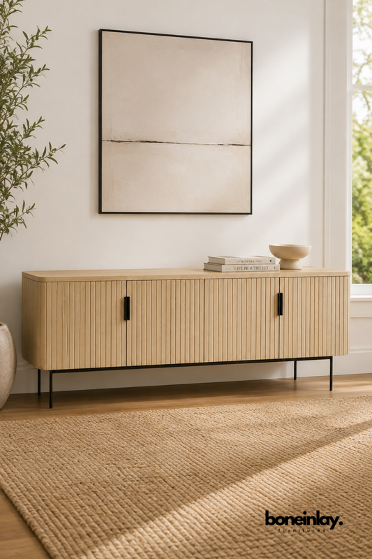 Light wood media console with a fluted, ribbed door panel design.
Four cabinet doors feature vertical grooved detailing for texture.
Rounded corners and slim black metal legs add a modern touch.
Styled beneath a framed abstract print in a bright, minimal room.