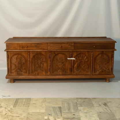 Hand carved menagerie media unit  in a front view, with warm natural wood, five animal relief doors and three drawers.