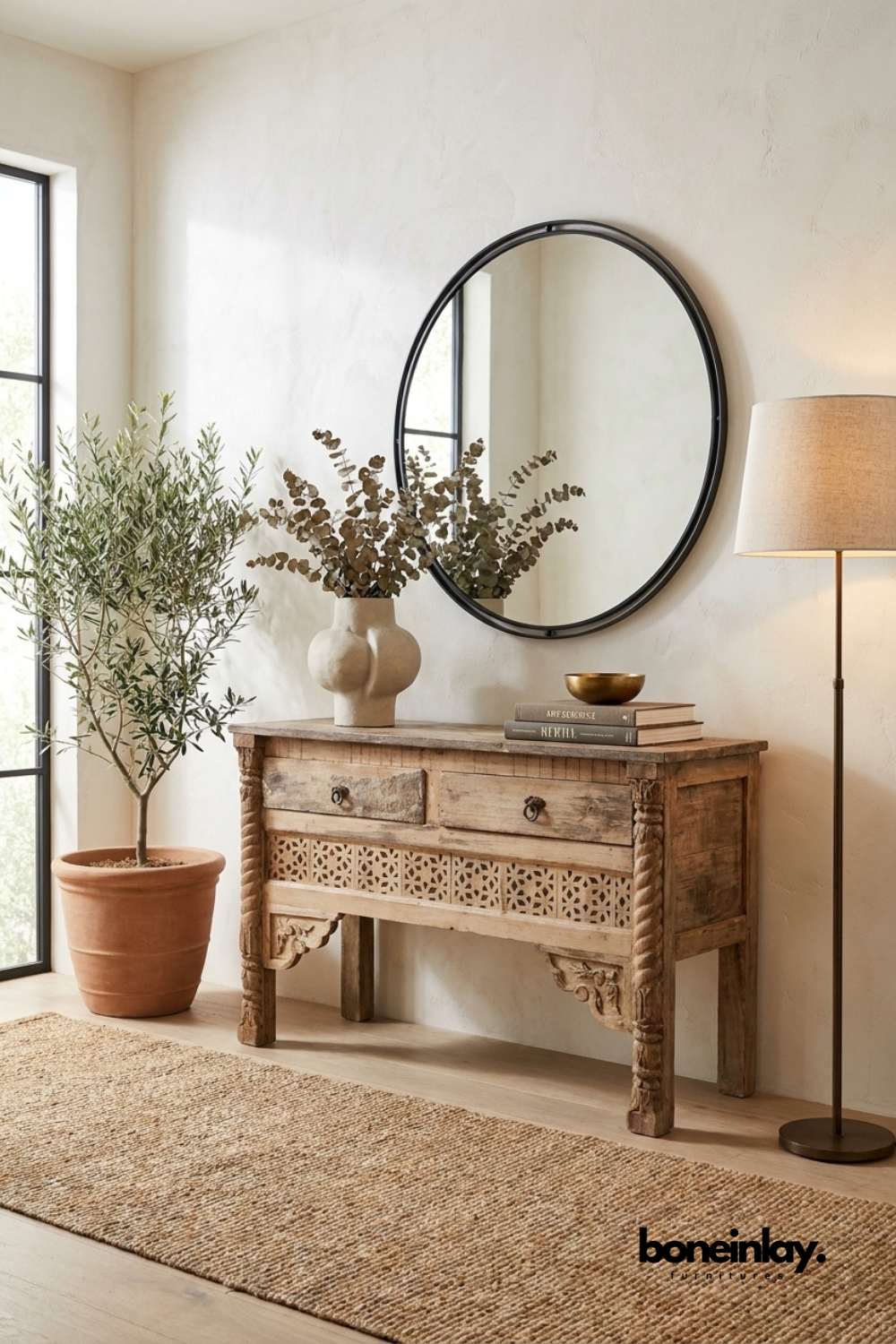 Hand-carved wood console table with a distressed natural finish.
Two front drawers sit above a carved jaali lattice panel.
Spiral-turned front legs add traditional artisanal detailing.
Styled beneath a round black-framed mirror in an entryway.