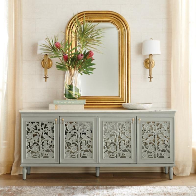 Hand carved peacock credenza in rustic solid wood, styled in living room beneath a gold-framed mirror with flowers.