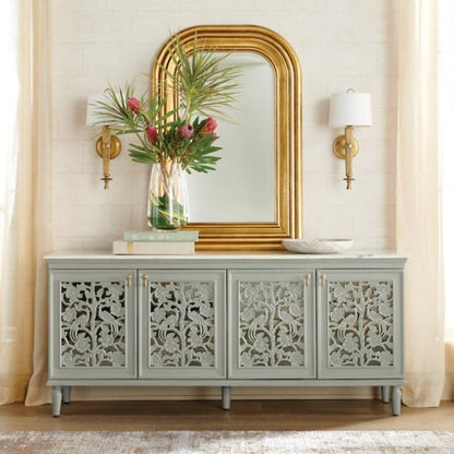Hand carved peacock credenza in rustic solid wood, styled in living room beneath a gold-framed mirror with flowers.