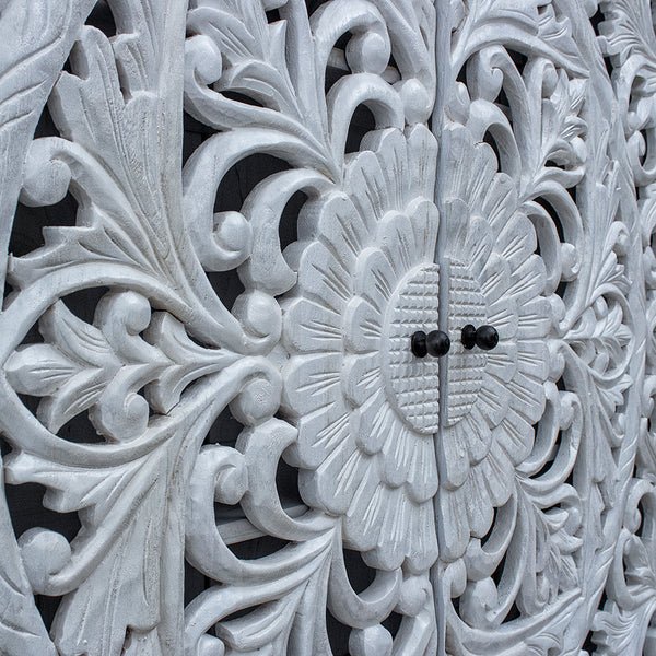Hand carved wood credenza in rustic, close-up of floral door carvings with curling vines and dark knobs.