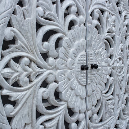 Hand carved wood credenza in rustic, close-up of floral door carvings with curling vines and dark knobs.