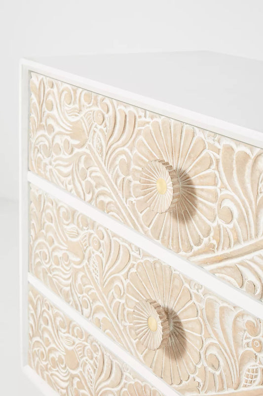 Close-up of Hand-carved wood dresser with six drawers, a natural finish and recessed pulls set into the textured fronts.