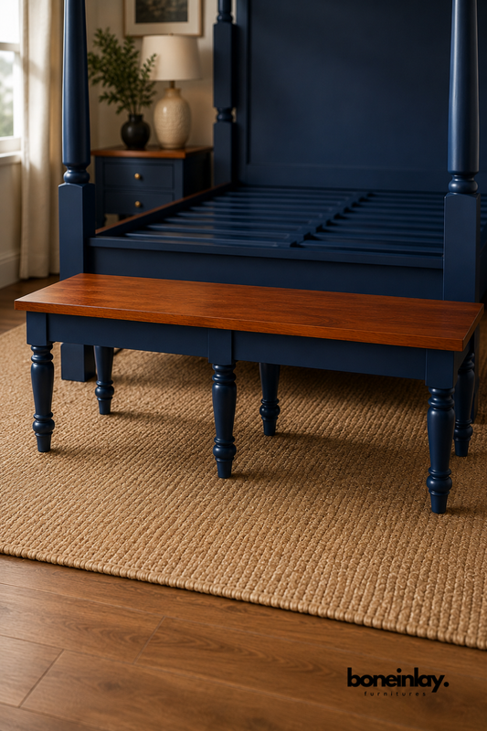 Long wood bench with a rich mahogany-tone tabletop and blue painted legs.
Six hand-turned wood legs provide sturdy, decorative support.
Solid wood plank top showcases natural grain and warm reddish-brown tone.
Photographed in a workshop beside a matching blue four-poster bed frame.