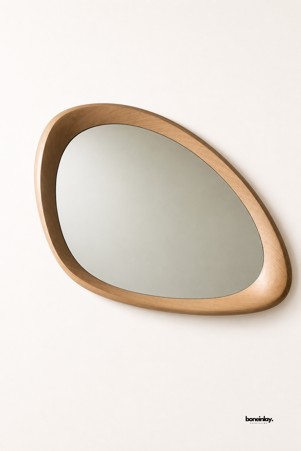 Artisan-crafted organic pebble-shaped wall mirror featuring a smooth sculpted solid oak frame with natural light wood graining and fluid asymmetrical contours. Set against a clean studio background, this contemporary accent mirror doubles as a striking piece of wall art and a functional vanity mirror for modern entryways, hallways, or living rooms.