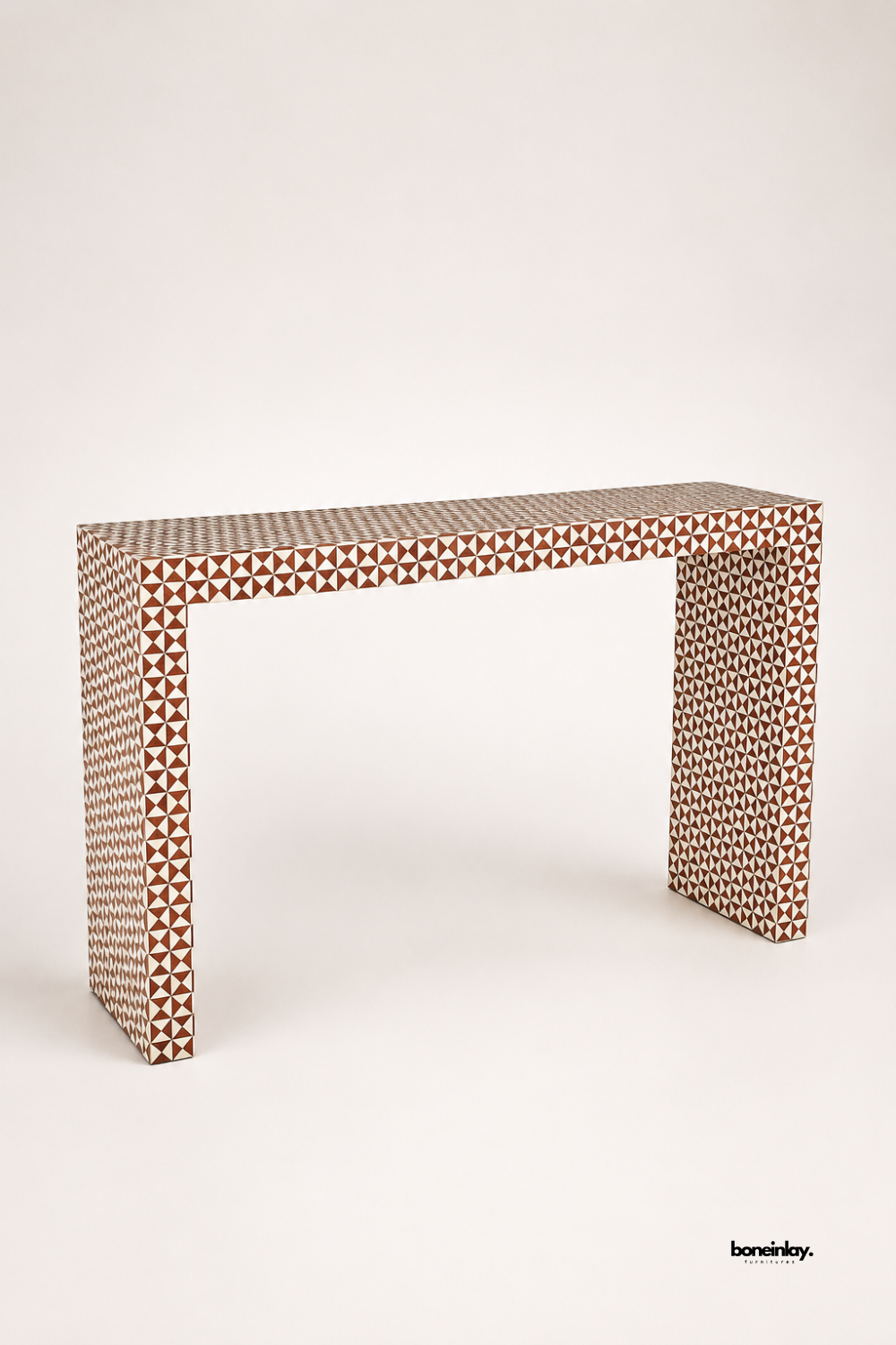Brown and ivory bone inlay console table featuring a dense geometric triangle mosaic pattern wrapping the entire surface. Clean waterfall-style legs create a sleek architectural silhouette in warm earthy tones. Photographed at an angle on a plain studio background to highlight the intricate inlay pattern. A striking statement console for entryways and modern interiors.