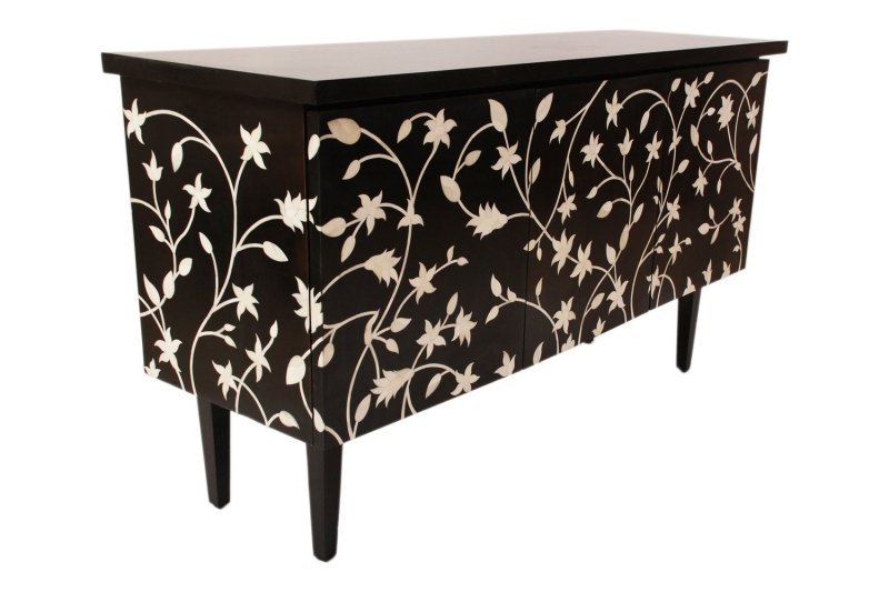 Close detail of ivory bone inlay floral and leaf motif hand-carved into black resin surface of artisan sideboard, showing craftsmanship texture