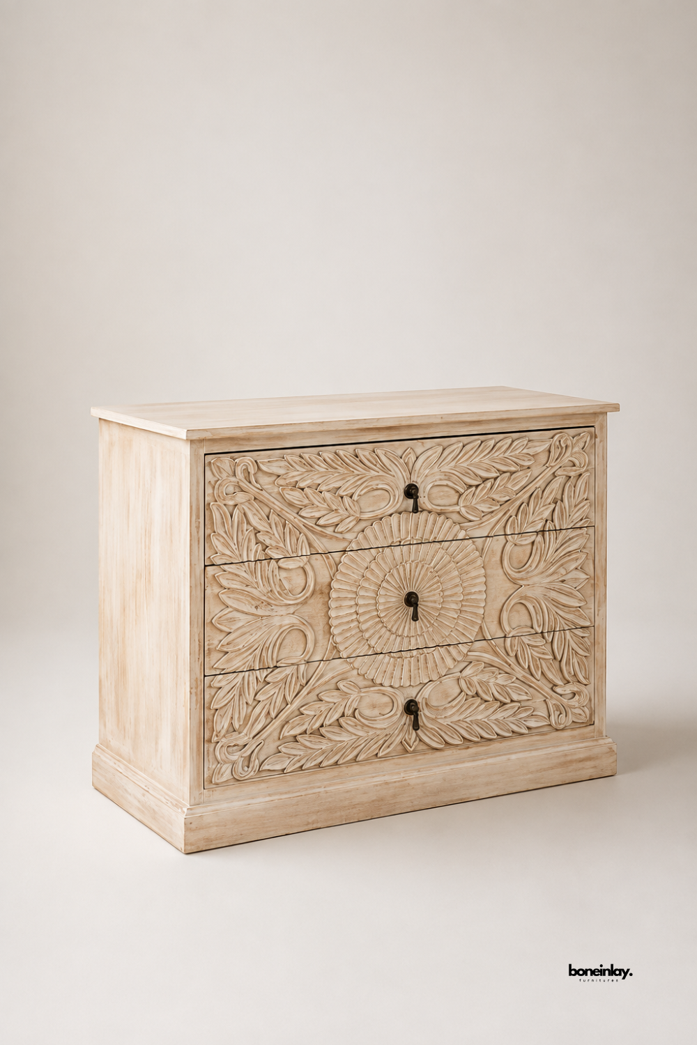 Artisan-crafted solid wood chest of drawers showcasing intricate floral leaf carvings, a central sunburst medallion motif, and a distressed whitewash finish. Set against a clean neutral studio background, this 3-drawer accent dresser offers ample organized storage, heirloom craftsmanship, and timeless coastal farmhouse style for modern living spaces.