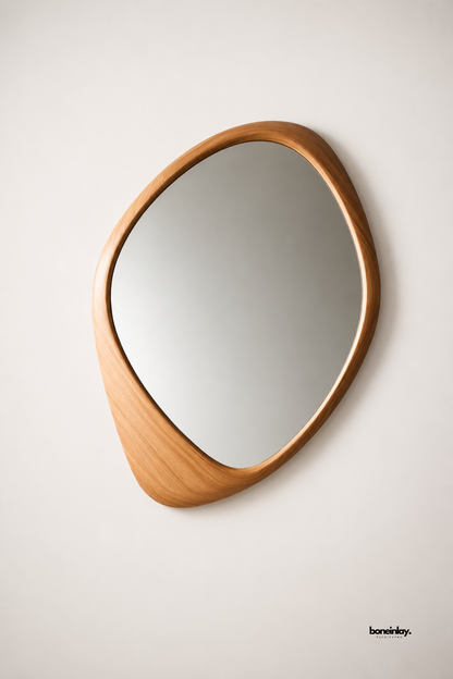 Hand-carved organic teardrop wooden mirror crafted from solid oak with smooth rounded bevels and an elongated asymmetrical base silhouette. Presented on a neutral studio backdrop, this mid-century modern statement mirror brings warm natural textures, Scandinavian minimalism, and sculptural elegance to luxury home decor.