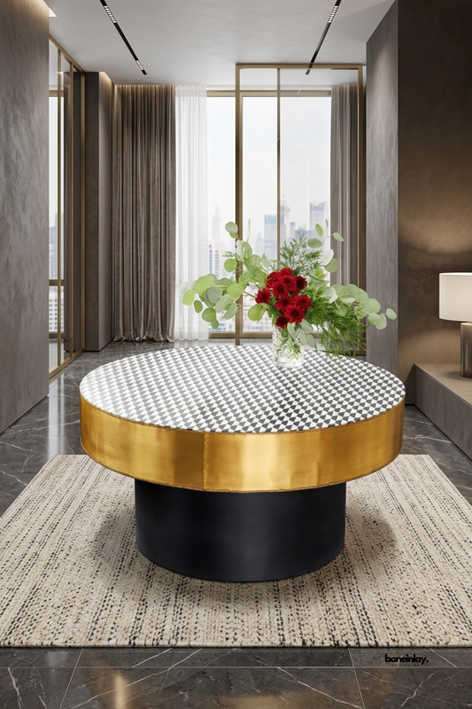 Modern round bone inlay coffee table showcasing a black and white harlequin diamond pattern top, a lustrous brushed gold metal border, and a bold black drum pedestal base. Styled in a luxury penthouse lounge on a neutral patterned rug with fresh floral decor, this statement center table elevates modern living rooms.